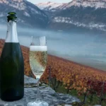 Bouteille de Crémant et flûte devant les vignes alpines