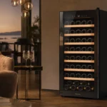 Sleek 28-bottle silent wine cooler with triple-glazed glass door in a modern living room setting, warm ambient lighting highl