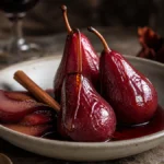 Whole pears poached in red wine and honey syrup with cinnamon in an elegant dessert bowl