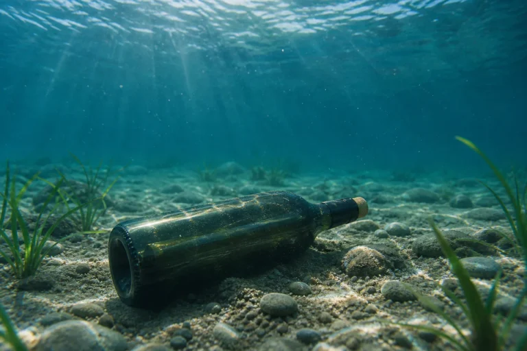 Une bouteille de vin couchée sur un fond sablonneux sous l'eau, éclairée par la lumière filtrant depuis la surface, illustran