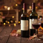 Elegant editorial photograph of premium French wine bottles displayed on a wooden table with crystal wine glasses, warm golde